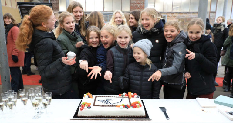 Glade børn samlet omkring en jubilæumskage på Gentofte Rideklub
